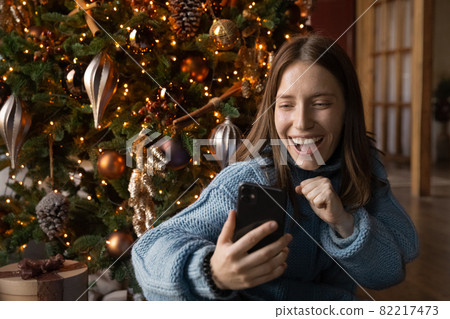Overjoyed young caucasian woman looking at cellphone screen. 82217473
