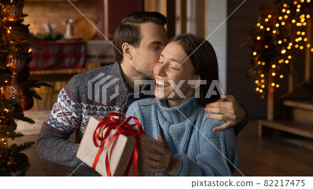 Affectionate loving young husband giving Christmas gift to wife. 82217475
