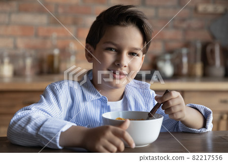 Head shot portrait smiling 8s boy eating corn cereal 82217556