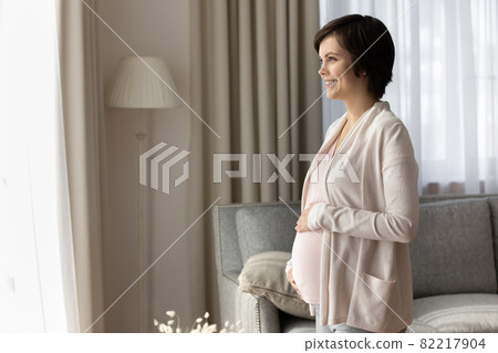 Carefree young expectant mother look at distance full of dreams Carefree young expectant mother look at distance full of dreams 82217904