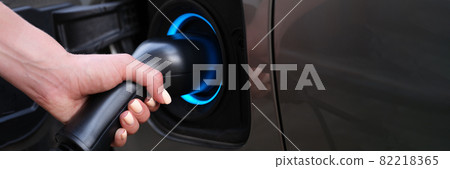 Woman charging car using electric plug closeup 82218365