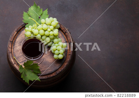 Red wine glass and white grape on old barrel 82218889
