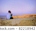 A young lover sitting on a cliff by the sea and watching the sunset 82218942