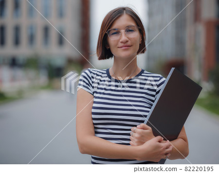 woman walking with laptop in city street woman walking with laptop in city street 82220195