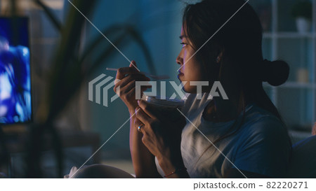 Asian woman eating and watching TV 82220271