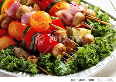vegetarian skewers with dry herbs on wooden skewers of zucchini tomato onion mushrooms on a plate vegetarian skewers with dry herbs on wooden skewers of zucchini tomato onion mushrooms on a plate 82220450