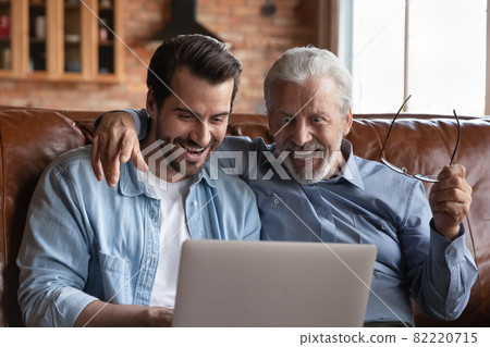 Overjoyed young man with mature father looking at laptop screen Overjoyed young man with mature father looking at laptop screen 82220715