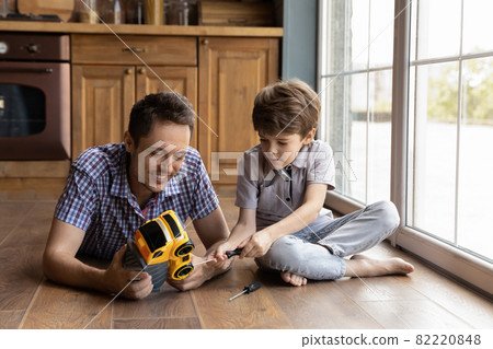 Smiling young father teaching little son repairing toy. Smiling young father teaching little son repairing toy. 82220848