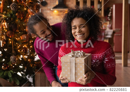 Happy biracial couple exchange presents on Christmas 82220881
