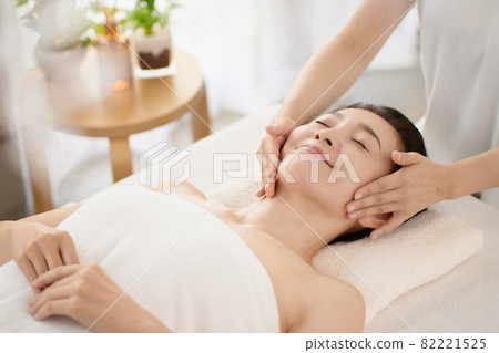 Middle-aged woman receiving a massage at an esthetic salon 82221525