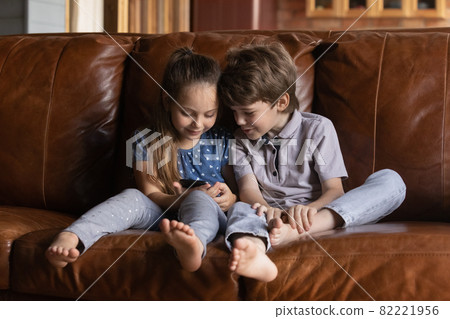 Happy adorable little children playing games on cellphone. Happy adorable little children playing games on cellphone. 82221956