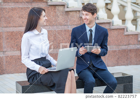 Boss and his assistant discussing their work outdoors. Boss and his assistant discussing their work outdoors. 82223757