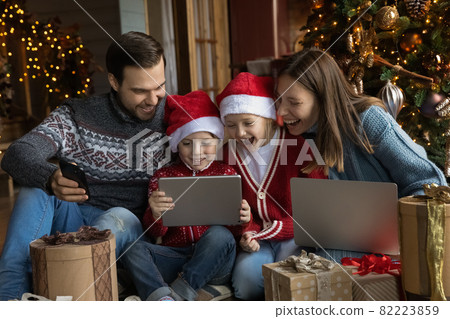 Happy young parents watching funny Christmas cartoons with kids. Happy young parents watching funny Christmas cartoons with kids. 82223859