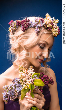 Happy young beautiful in a lilac wreath with white skin background blue, with white daylight 82225371