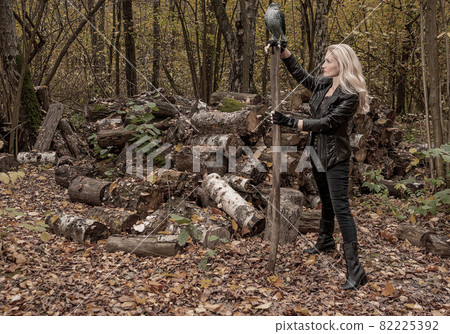 In the forest, a girl stands in a leather jacket and black jeans. Beautiful looking at camera wellbeing concept 82225392