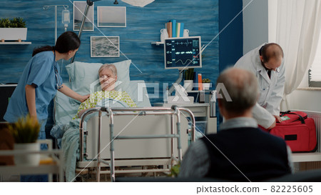 Elder woman with sickness receiving visit from doctor and nurse 82225605
