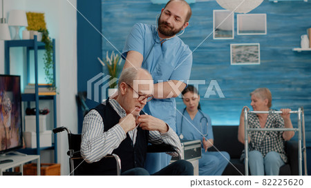 Medical assistant consulting disabled man with stethoscope Medical assistant consulting disabled man with stethoscope 82225620