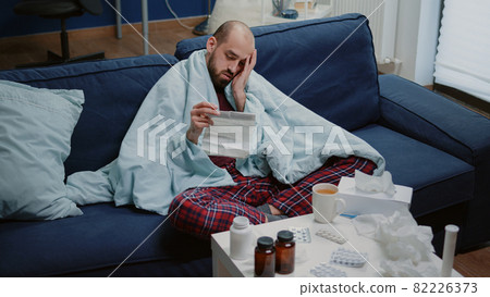Man with sickness reading medicament information leaflet 82226373