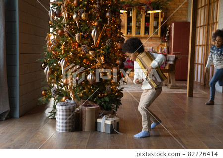 Happy ethnic kids unpack boxes for Christmas 82226414