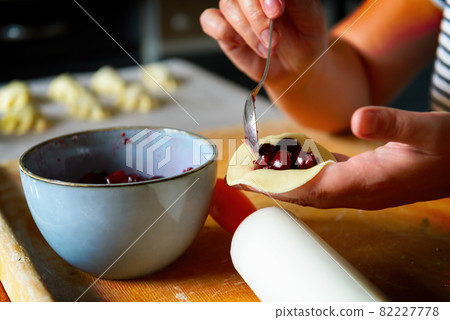 Making dumplings filled with sour cherry with sugar Making dumplings filled with sour cherry with sugar 82227778