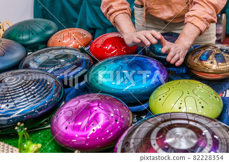 Exhibition and sale of unusual musical instruments - tank drum. Man plays one of them. Exhibition and sale of unusual musical instruments - tank drum. Man plays one of them. 82228354