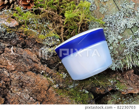 Cosmetic jar with blue screw cap and green forest moss. Front view, mockup. Cosmetic bottle container with white moisturizer for branding of medicine or cosmetics. Cosmetic jar with blue screw cap and green forest moss. Front view, mockup. Cosmetic bottle container with white moisturizer for branding of medicine or cosmetics. 82230703