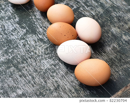 White and brown eggs of domestic hens on old wooden gray painted texture background. Closeup White and brown eggs of domestic hens on old wooden gray painted texture background. Closeup 82230704