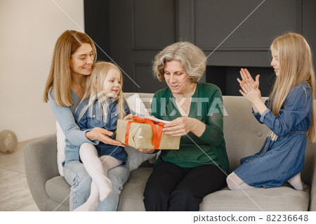 Family is sitting on the sofa and have a boxes with presents 82236648