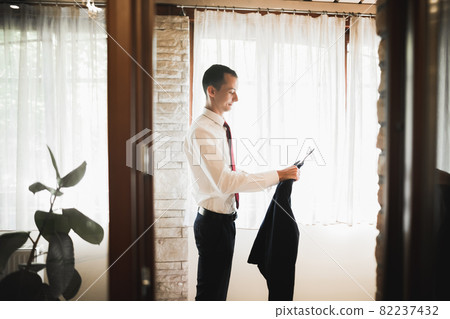 Grooms morning preparation. Handsome man getting dressed and preparing for the wedding 82237432