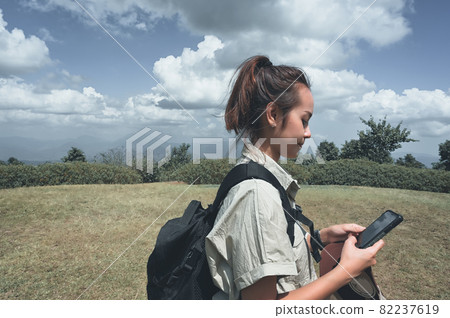 Side view point of young women backpacker using GPS smart phone to finding a direction for navigate to destination Side view point of young women backpacker using GPS smart phone to finding a direction for navigate to destination 82237619