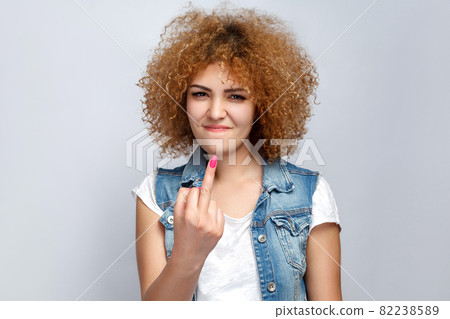 Portrait of crazy curly mixed race girl in casual style is showing middle finger and looking at camera. Portrait of crazy curly mixed race girl in casual style is showing middle finger and looking at camera. 82238589