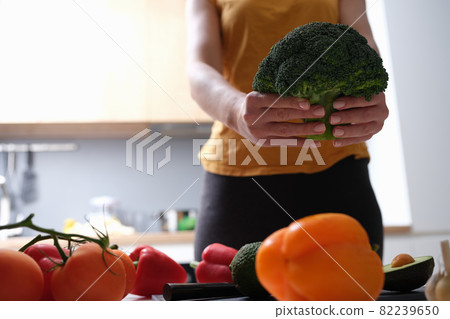 Female housewife holding broccoli in her hands in kitchen closeup Female housewife holding broccoli in her hands in kitchen closeup 82239650