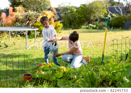 Happy caucasian sister and brother watering plants together 82245733