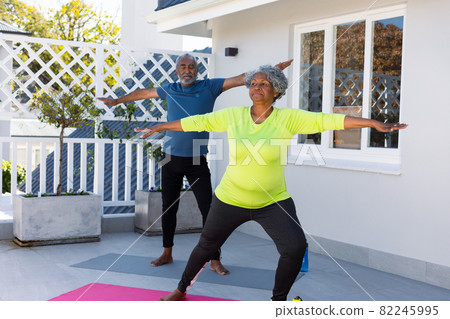 Focused african american senior couple practicing yoga in garden Focused african american senior couple practicing yoga in garden 82245995