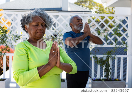 Focused african american senior couple practicing yoga in garden Focused african american senior couple practicing yoga in garden 82245997