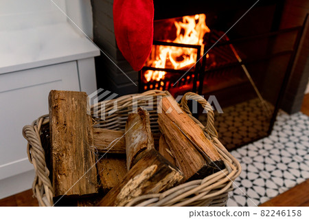 Logs of wood in basket lying at fireplace wit christmas sock 82246158