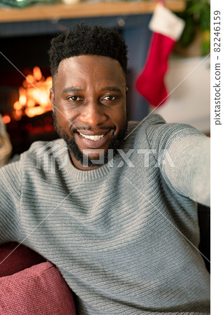 Happy african american man taking selfie, christmas decorations in background 82246159