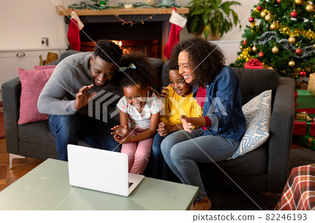 Happy african american family having video call on laptop, christmas decorations in background 82246193