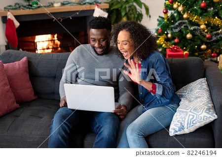 Happy african american couple having video call on laptop, christmas decorations in background 82246194