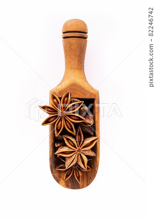 Close up chinese star anise in wooden scoop isolate on white background. Dried star anise spice fruits top view. Close up chinese star anise in wooden scoop isolate on white background. Dried star anise spice fruits top view. 82246742