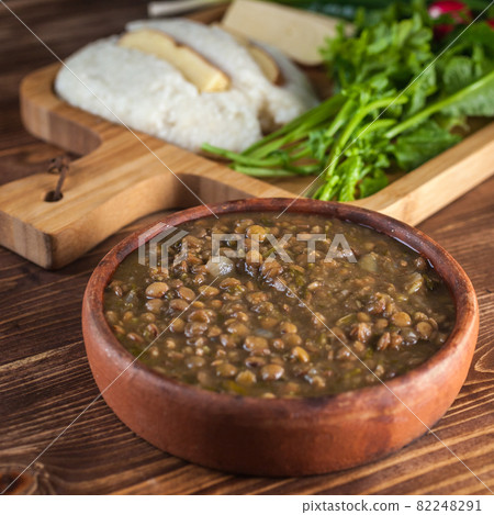 Mengrelian corn mamalica (ghomi) with cheese and lentls in ceramic dish (ketsi). Georgian traditional food Mengrelian corn mamalica (ghomi) with cheese and lentls in ceramic dish (ketsi). Georgian traditional food 82248291