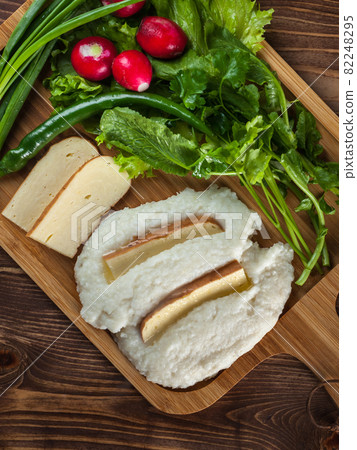 Mengrelian corn mamalica (ghomi) with cheese and various herb on wooden table. Georgian traditional food 82248295