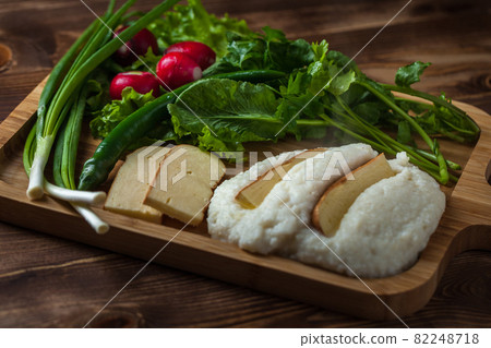 Mengrelian corn mamalica (ghomi) with cheese and various herb on wooden table. Georgian traditional food Mengrelian corn mamalica (ghomi) with cheese and various herb on wooden table. Georgian traditional food 82248718