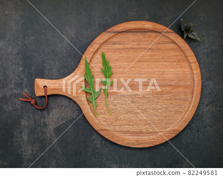 Empty wooden pizza platter set up on dark concrete. Pizza tray on dark concrete background flat lay and copy space. Empty wooden pizza platter set up on dark concrete. Pizza tray on dark concrete background flat lay and copy space. 82249581