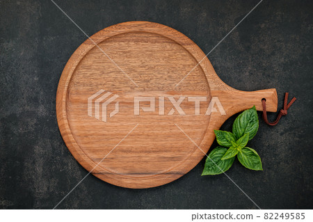 Empty wooden pizza platter set up on dark concrete. Pizza tray on dark concrete background flat lay and copy space. Empty wooden pizza platter set up on dark concrete. Pizza tray on dark concrete background flat lay and copy space. 82249585