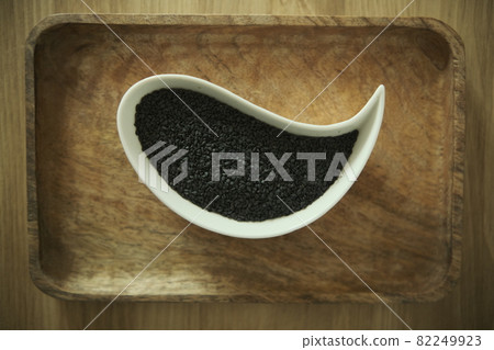 black sesame seeds on a white plate. Wooden table. Soft selective blurred background black sesame seeds on a white plate. Wooden table. Soft selective blurred background 82249923