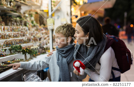 Tween boy with mother looking for Christmas decorations on street market 82251177
