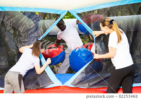 Adult fun friends box in huge boxing gloves in an amusement park 82253468