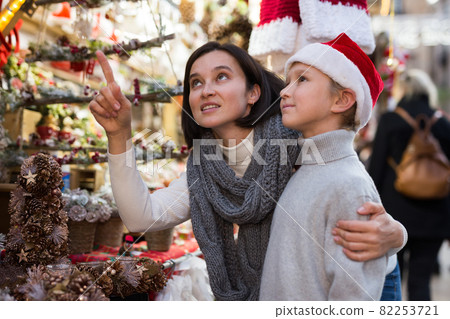 Tween boy with mother choosing Xmas decorations on street fair Tween boy with mother choosing Xmas decorations on street fair 82253721