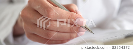 Woman doctor writes patient data into documents with pen Woman doctor writes patient data into documents with pen 82254372